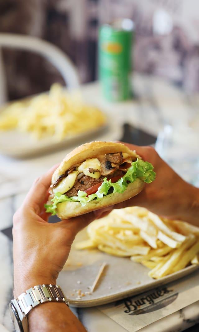 Burger held at the table with fries alongside