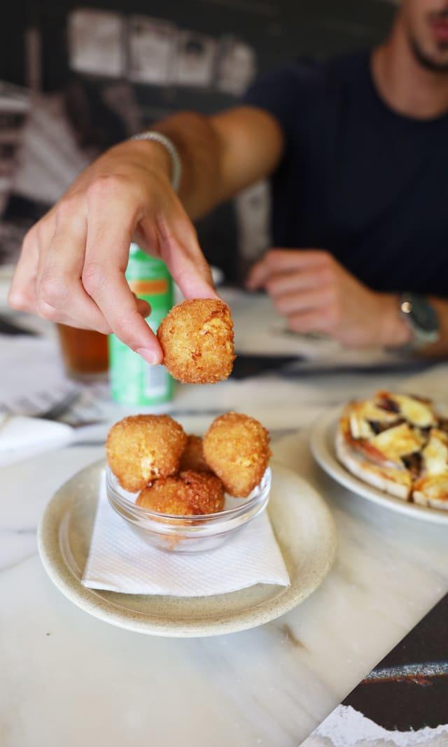 Hand dipping a croquette into sauce at the table