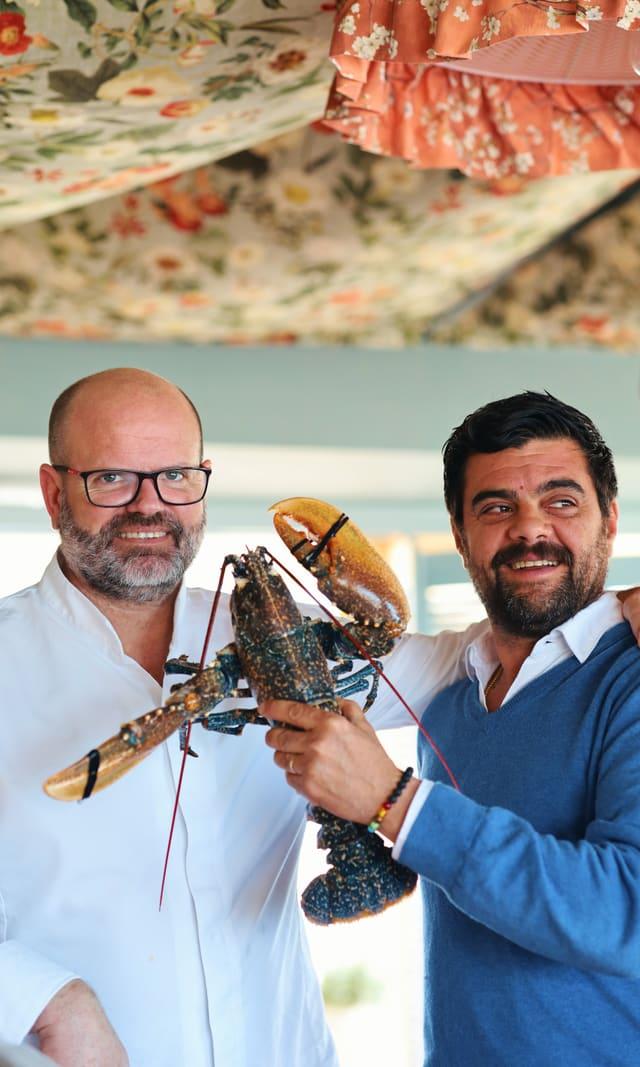 Two cooks holding a lobster in the kitchen