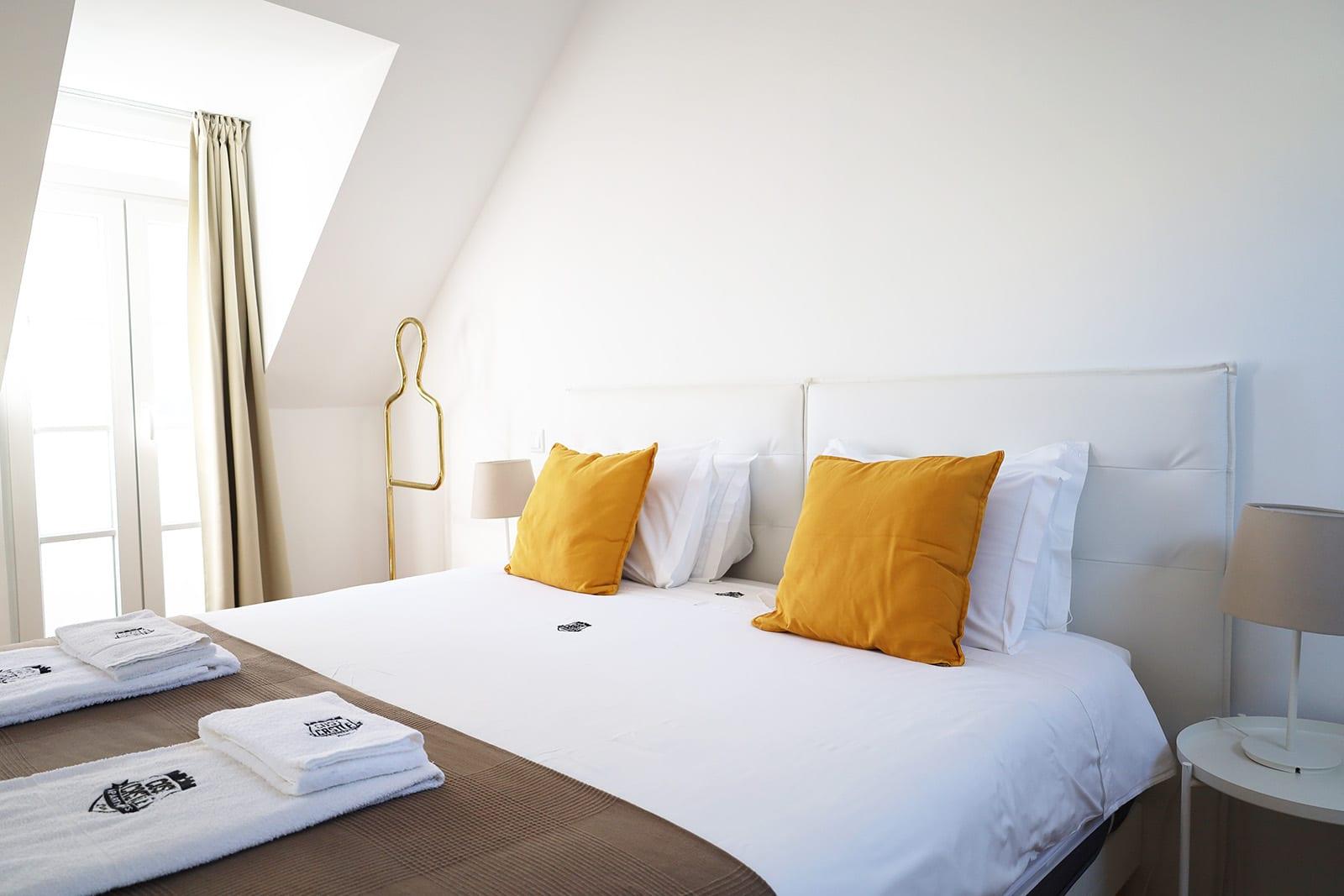 Hotel room with a white bed and mustard cushions